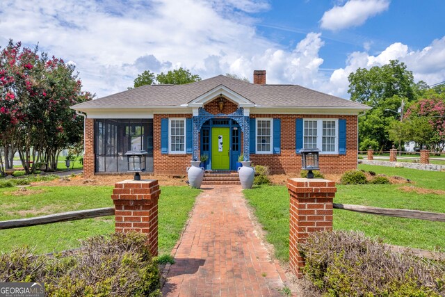 view of front of home featuring a sunroom and a front lawn