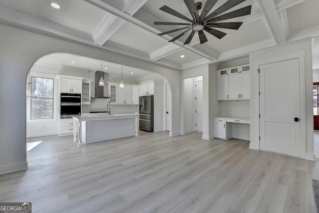 kitchen with decorative light fixtures, white cabinets, a center island, stainless steel appliances, and wall chimney exhaust hood