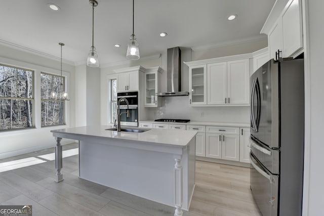 kitchen featuring sink, white cabinetry, appliances with stainless steel finishes, pendant lighting, and wall chimney range hood