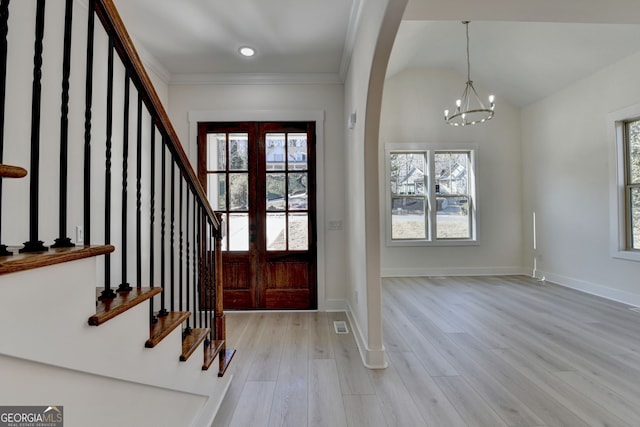 entryway featuring ornamental molding, lofted ceiling, a chandelier, and light hardwood / wood-style flooring