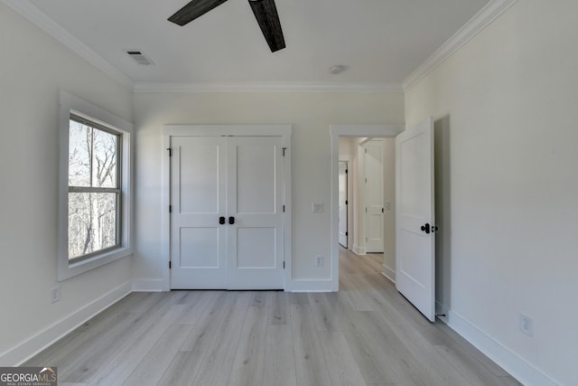 unfurnished bedroom featuring ceiling fan, ornamental molding, light hardwood / wood-style floors, and a closet