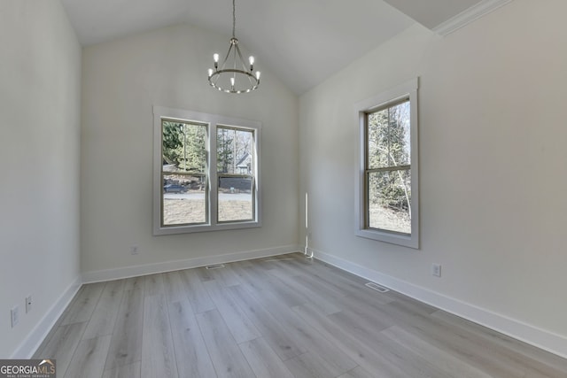 unfurnished room featuring an inviting chandelier, a healthy amount of sunlight, vaulted ceiling, and light hardwood / wood-style floors