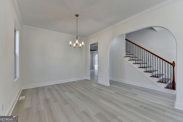 spare room with ornamental molding, an inviting chandelier, and light wood-type flooring