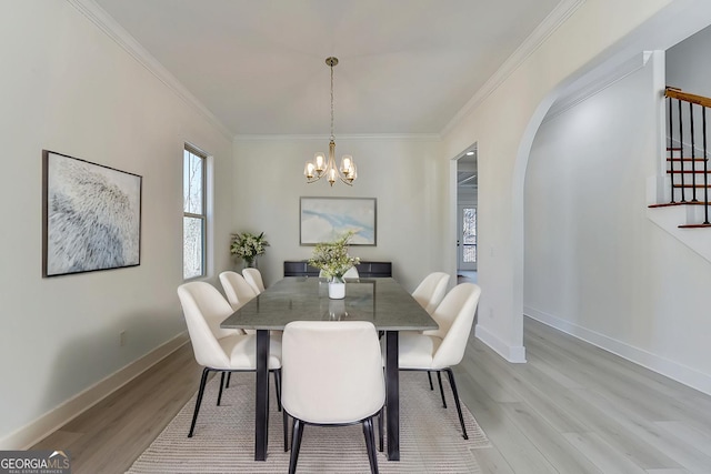 dining area with ornamental molding, a chandelier, and light hardwood / wood-style flooring