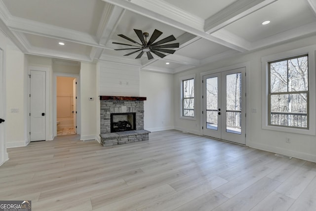 unfurnished living room with french doors, coffered ceiling, a stone fireplace, and light hardwood / wood-style flooring