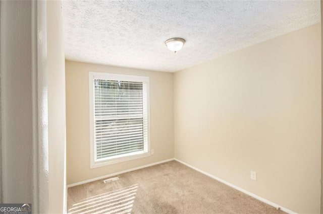 spare room featuring light carpet and a textured ceiling