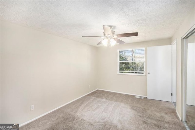 carpeted empty room with a textured ceiling and ceiling fan