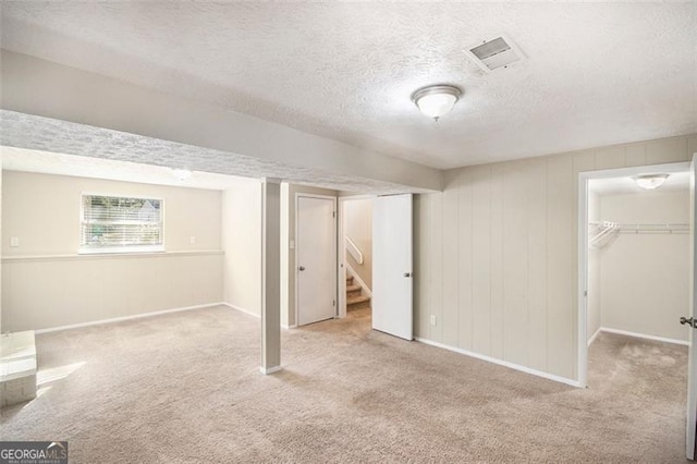 basement with a textured ceiling and light carpet