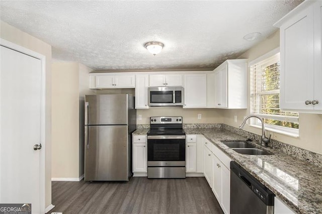 kitchen with sink, light stone counters, stainless steel appliances, and white cabinetry