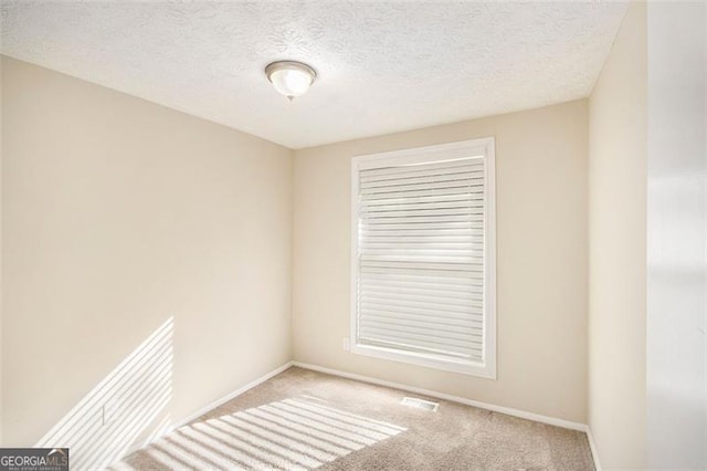 carpeted spare room featuring a textured ceiling