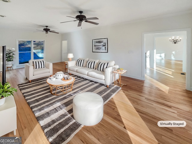 living room featuring ceiling fan with notable chandelier and light hardwood / wood-style flooring