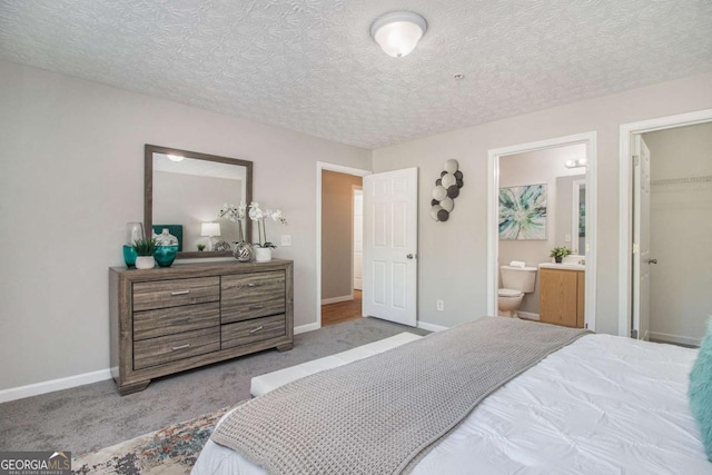 carpeted bedroom with a textured ceiling, a closet, a spacious closet, and ensuite bathroom