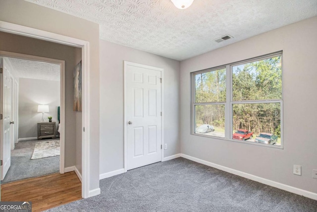 unfurnished bedroom with a textured ceiling and carpet