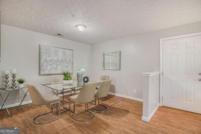 dining area featuring light hardwood / wood-style floors and a textured ceiling