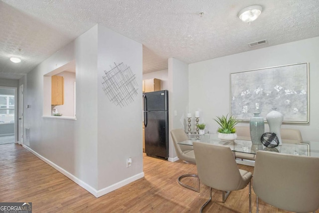 dining area with light hardwood / wood-style floors and a textured ceiling