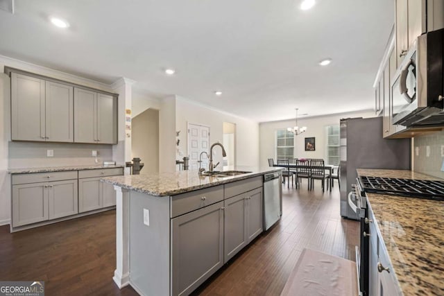 kitchen featuring pendant lighting, appliances with stainless steel finishes, an island with sink, sink, and gray cabinetry