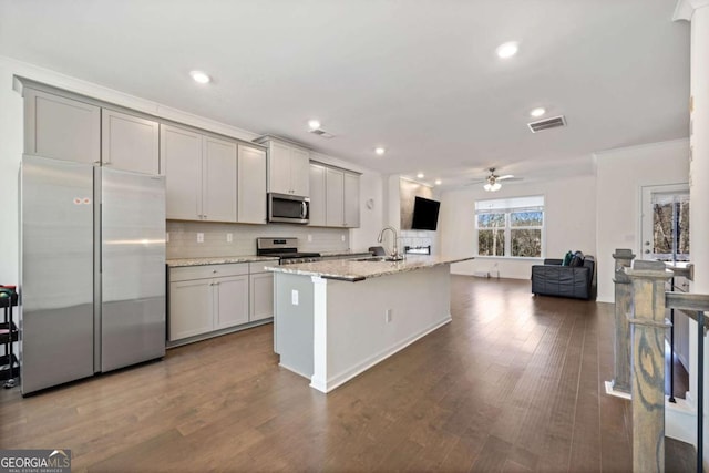 kitchen featuring light stone countertops, stainless steel appliances, an island with sink, sink, and gray cabinets
