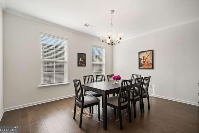 dining space with dark hardwood / wood-style flooring, crown molding, and a notable chandelier
