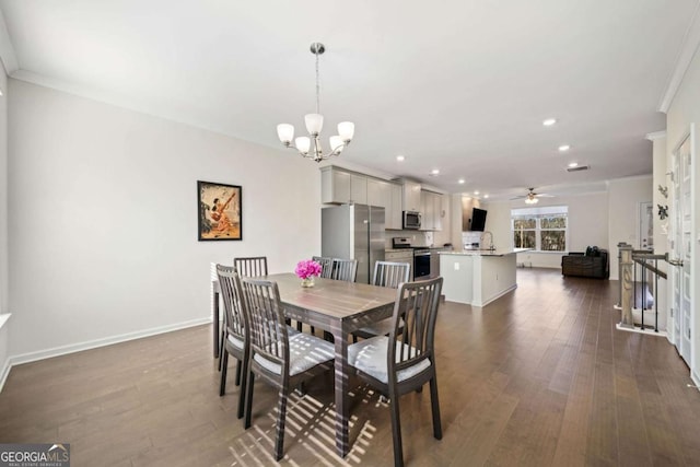 dining room with dark hardwood / wood-style flooring, crown molding, ceiling fan with notable chandelier, and sink