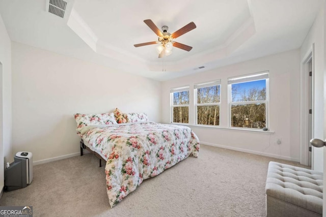 carpeted bedroom featuring ceiling fan and a raised ceiling