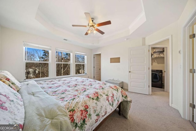 carpeted bedroom featuring ceiling fan, a closet, a raised ceiling, and washer / clothes dryer