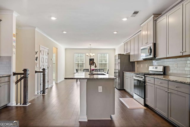 kitchen with a center island with sink, appliances with stainless steel finishes, gray cabinetry, light stone counters, and sink