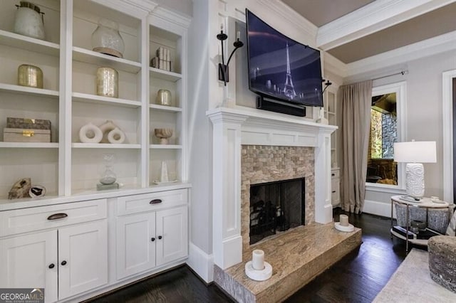 living room featuring dark wood-type flooring, built in shelves, ornamental molding, and a fireplace