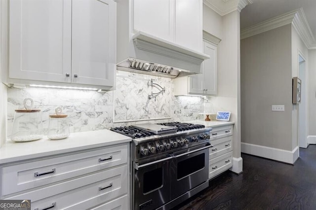 kitchen featuring dark hardwood / wood-style floors, white cabinetry, range with two ovens, ornamental molding, and custom range hood