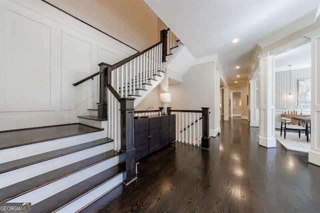 stairs with wood-type flooring, ornamental molding, and ornate columns