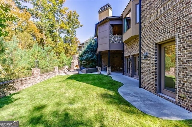 view of yard featuring a patio and exterior fireplace