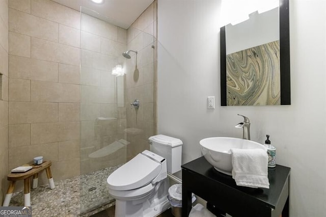 bathroom with vanity, toilet, and tiled shower