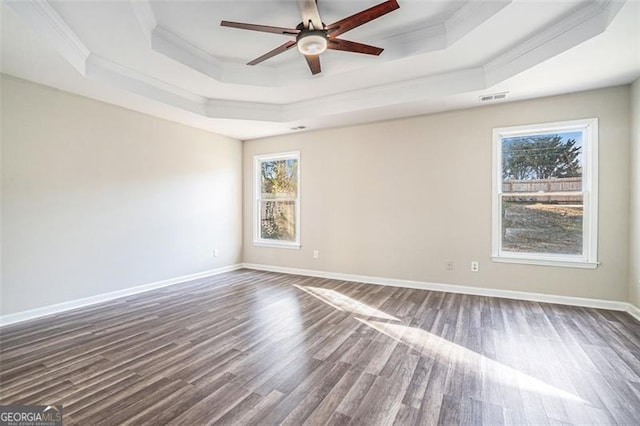 empty room featuring a raised ceiling, ceiling fan, dark hardwood / wood-style flooring, and crown molding