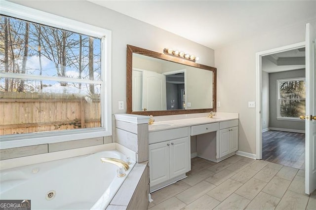 bathroom featuring a relaxing tiled tub and vanity