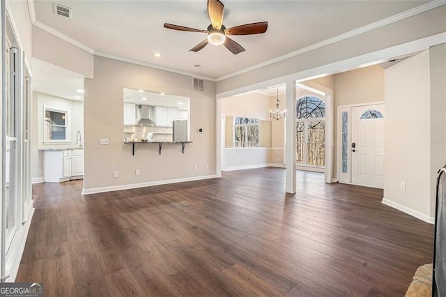 unfurnished living room with dark wood-type flooring, ornamental molding, and ceiling fan with notable chandelier