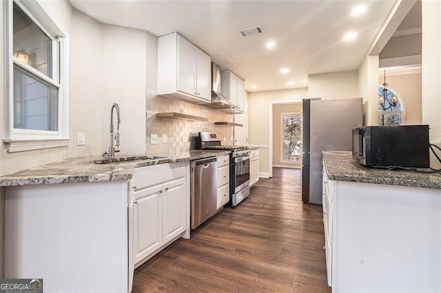 kitchen with sink, dark wood-type flooring, appliances with stainless steel finishes, white cabinets, and dark stone counters