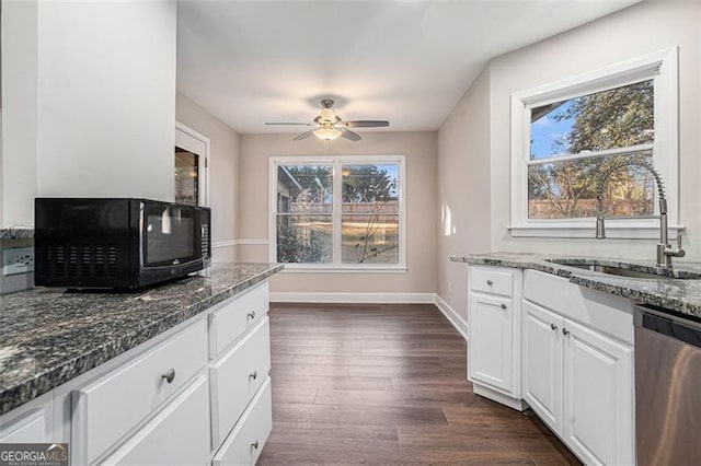 kitchen with dark hardwood / wood-style floors, dark stone countertops, dishwasher, white cabinets, and sink