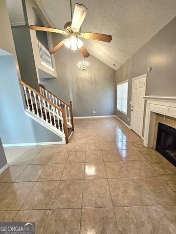 unfurnished living room featuring light tile patterned floors, a tile fireplace, ceiling fan, high vaulted ceiling, and a textured ceiling