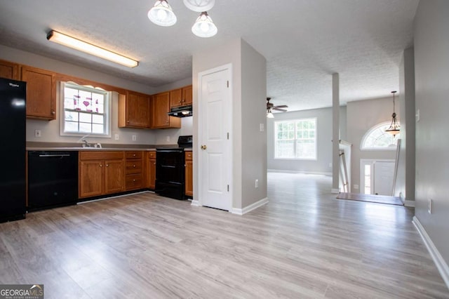 kitchen featuring a textured ceiling, pendant lighting, light hardwood / wood-style flooring, and black appliances