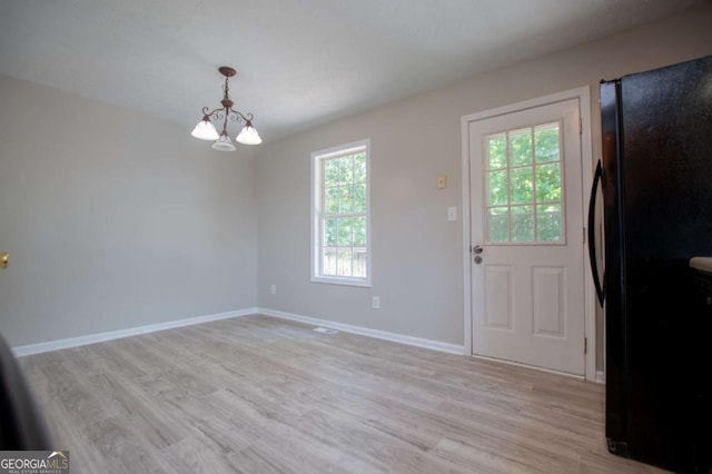 interior space with a notable chandelier and light hardwood / wood-style flooring