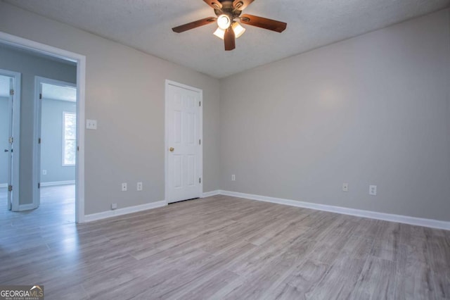 empty room with a textured ceiling, ceiling fan, and light hardwood / wood-style floors