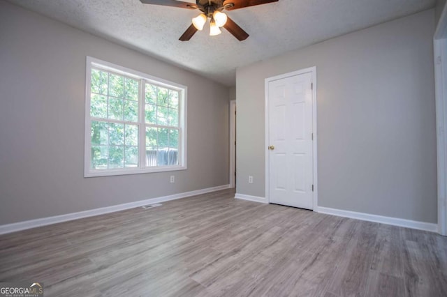 unfurnished bedroom with ceiling fan, a textured ceiling, and light wood-type flooring