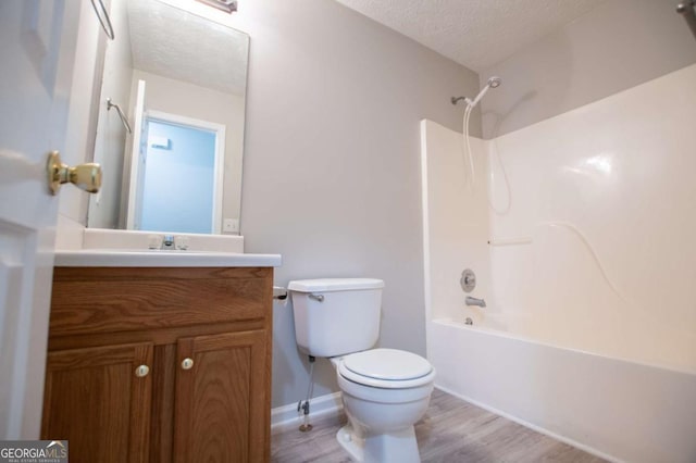 full bathroom with a textured ceiling, wood-type flooring, washtub / shower combination, vanity, and toilet