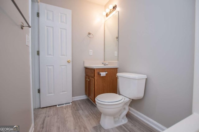 bathroom featuring toilet, vanity, and hardwood / wood-style floors