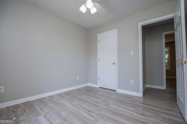 unfurnished bedroom with light wood-type flooring, ceiling fan, and a textured ceiling