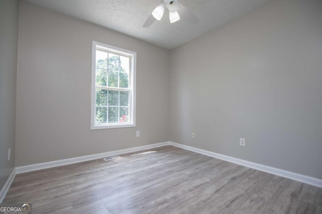 unfurnished room featuring ceiling fan, light wood-type flooring, and a textured ceiling