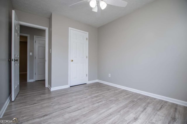 unfurnished bedroom featuring ceiling fan, a textured ceiling, light hardwood / wood-style flooring, and a closet