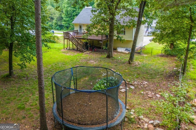 view of yard featuring a wooden deck and a trampoline