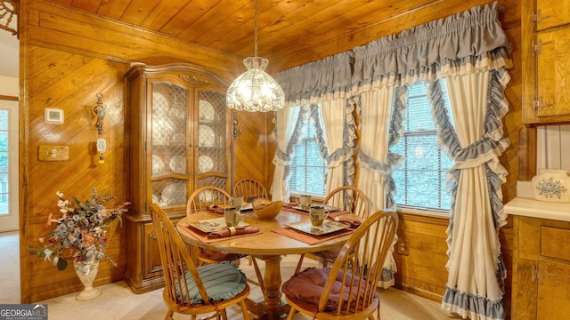 dining room with light carpet, an inviting chandelier, wood ceiling, and wooden walls