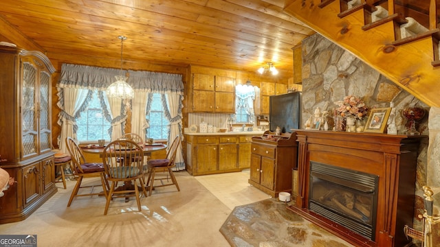 kitchen featuring wooden ceiling, a notable chandelier, a fireplace, light colored carpet, and pendant lighting