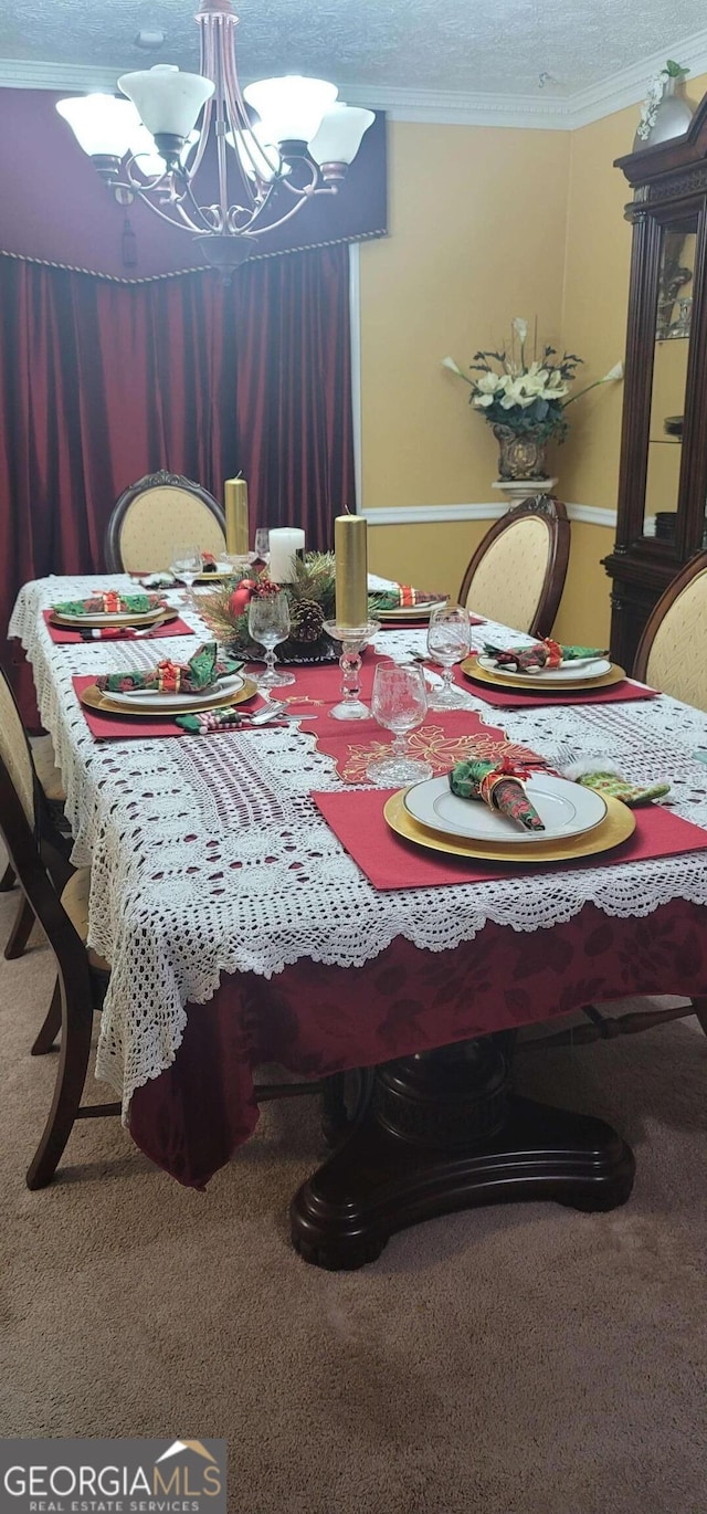 dining room featuring a textured ceiling, ornamental molding, a chandelier, and carpet